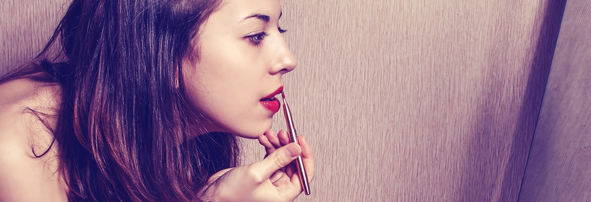 The girl paints lips with lipstick looking in the mirror Woman applying lipstick